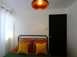 ein Schlafzimmer mit einem Bett mit gelben und orangefarbenen Kissen in der Unterkunft StayPlus Metro Eclectic Glam 1BR in Manila