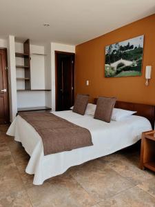 1 cama blanca grande en una habitación con paredes de color naranja en Hotel Milán, en Duitama