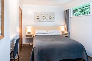 um quarto com uma cama, 2 candeeiros e uma janela em Dunrovin Motel em Taupo