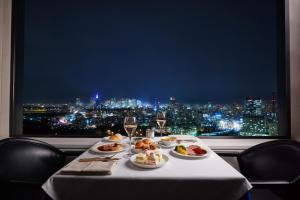 a table with food and wine glasses and a window at Hotel New Otani Tokyo The Main in Tokyo