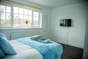 a white bedroom with a bed with a tv on it at 5 bedroom semi-detached house- 3 double beds - 2 single beds in Birmingham