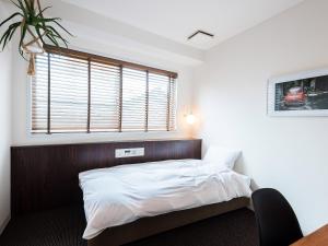 a bedroom with a bed with a wooden headboard and a window at Hotel Pacific Kanazawa in Kanazawa