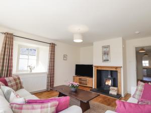 a living room with a fireplace and a tv at East Balachladich in Muir of Ord