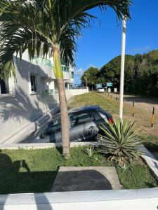 a car parked next to a building with a palm tree at Flat Beira Mar Carapibus in Conde