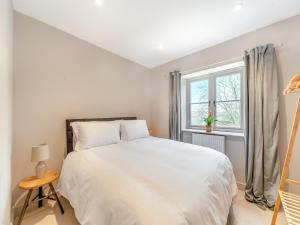 ein weißes Schlafzimmer mit einem Bett und einem Fenster in der Unterkunft Nixey Cottage in Turville