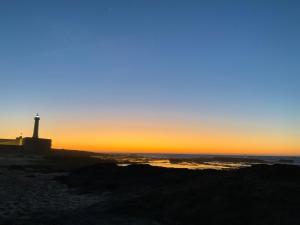 un faro sulla spiaggia con il tramonto sullo sfondo di House Naïma a Rabat
