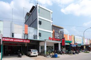 a building on the side of a street with cars parked in front at RedDoorz near Hang Nadim Batam Airport in Nongsa