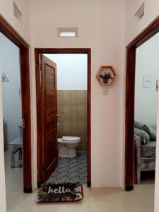 a bathroom with a toilet and a open door at rindoe jogja holiday home in Yogyakarta
