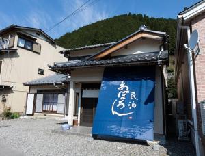 un bâtiment avec une porte bleue sur laquelle il est écrit dans l'établissement あぽろん, à Gujō