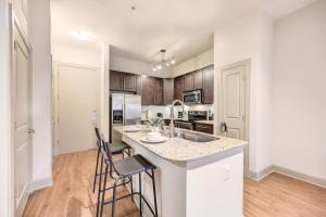 a kitchen with a sink and two bar stools at Beautiful 1Br/NRG/Pool/Wi-Fi/PetsOK/Garage parking in Houston
