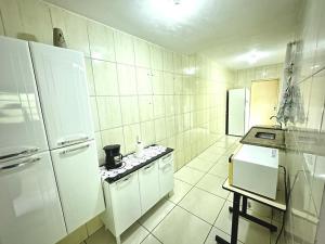 a kitchen with white appliances and a white tiled wall at Sonho meu in Guaratinguetá