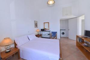 a bedroom with a white bed and a television at Icarus home in Kouniádhoi