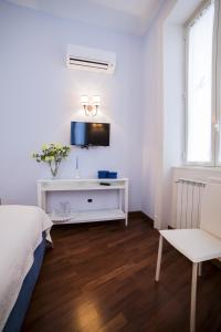 een witte slaapkamer met een bed en een televisie bij Mata e Grifone B&B in Messina