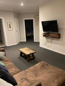 ein Wohnzimmer mit einem Sofa, einem TV und einem Tisch in der Unterkunft 13th Apostle Accommodation in Princetown