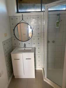a bathroom with a sink and a shower with a mirror at 13th Apostle Accommodation in Princetown