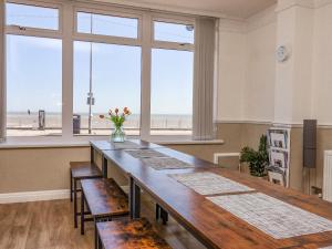 une salle à manger avec une longue table et des chaises ainsi qu'une plage dans l'établissement Southdowne, à Bridlington