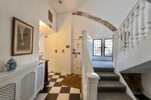 a hallway with a staircase with a checkered floor at Butley Priory in Woodbridge