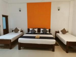 a bedroom with two beds and an orange and white wall at The Yala City Guest House in Tissamaharama