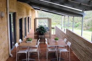 eine Terrasse mit Holztischen und -stühlen auf einem Gebäude in der Unterkunft 13th Apostle Accommodation in Princetown