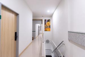 a hallway with white walls and a white stair case at Urbanview Hotel R House Batam in Jabi