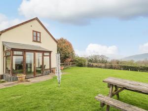 una casa con un patio verde con un banco en Penrose Cottage en Gilwern