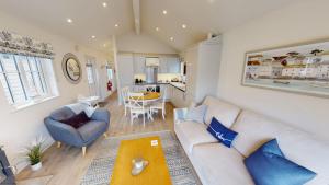 a living room with a white couch and a blue chair at Bay Breeze - Part of the The Bay Filey Holiday Village with pool, gym and direct beach access, pub, restaurant, tennis and meadows walks in Filey