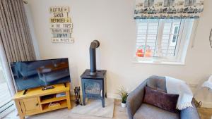 a living room with a television and a stove at Bay Breeze - Part of the The Bay Filey Holiday Village with pool, gym and direct beach access, pub, restaurant, tennis and meadows walks in Filey