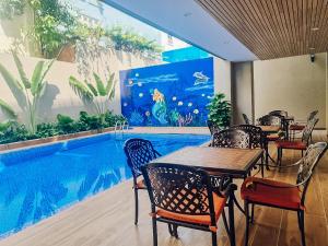 ein Restaurant mit einem Pool, Tischen und Stühlen in der Unterkunft Sabina Luxury Boutique Hotel & Villa in Vũng Tàu