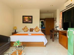 Dormitorio con cama, escritorio y TV en Da Bungalows, en Kata Beach
