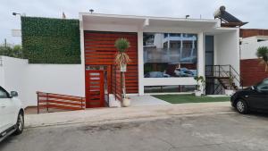 una casa con una puerta roja y un coche aparcado fuera en Suites & Habitaciones Acapulco La Lisera, en Arica