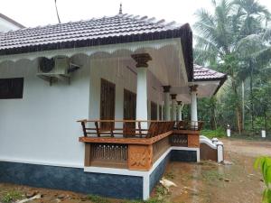 a house with a balcony in front of it at Kizhakkethottam Homestays-River View Villa in Pala