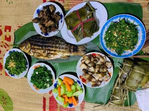 um prato de comida com peixe e legumes numa mesa em Tay Farmhouse em Ha Giang