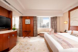 Hangzhou Xinqiao Hotel في هانغتشو: غرفة فندقية بسرير وتلفزيون بشاشة مسطحة