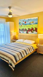 a bedroom with a large bed with a painting on the wall at Dunsborough Beach House in Quindalup