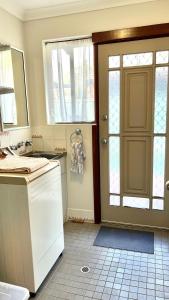 a kitchen with a door and a sink and a counter at Dunsborough Beach House in Quindalup