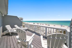 a deck with white chairs and the beach at Three Steps to the Beach Townhouse in Inlet Beach