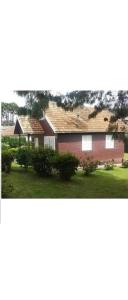 una casa con una casa roja con un patio en Chale de Madeira - Lareira e Fogueira---lindo gramado com mesa para café da manhã, churrasqueira e fogueira, en Campos do Jordão