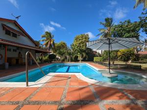 a swimming pool with an umbrella next to a house at Capi´s Place in San Andrés