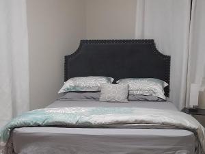 uma cama com cabeceira preta e almofadas em Ultimate Chill Brown's Town em Browns Town