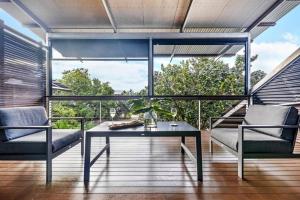 a room with a table and chairs on a balcony at 'Troppo' Darwin Designer Luxury Boutique Home in Paraparap