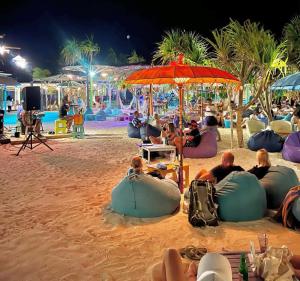 a group of people sitting on a beach at night at La Villa Loca in Gili Air
