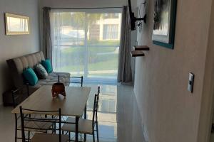 a living room with a table and chairs and a couch at Bonito departamento en planta baja en Manzanillo con Alberca in Manzanillo