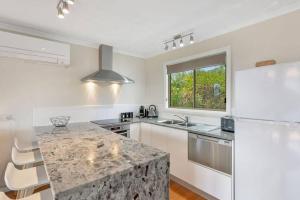 a kitchen with a granite counter top and a sink at Too Tyred - Binalong Bay in Binalong Bay