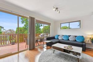 a living room with a couch and a balcony at Too Tyred - Binalong Bay in Binalong Bay