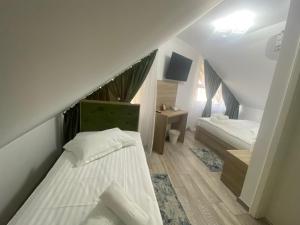 a attic bedroom with two beds and a tv at VILA DAVELY in Câmpulung Moldovenesc