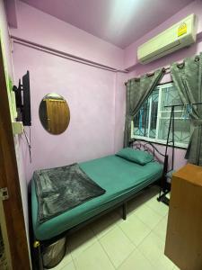 a small room with a green bed and a window at Sötnos in Jomtien Beach