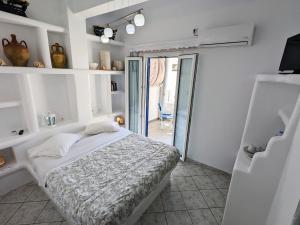 sypialnia z łóżkiem i drzwiami do pokoju w obiekcie Anoi Rooms w mieście Tinos