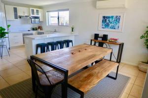 a kitchen with a wooden table and some chairs at Sunshine Coast Beach House - 2 mins to beach in Parrearra
