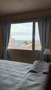 a bedroom with a bed and a window with the ocean at Apart km4 in Comodoro Rivadavia