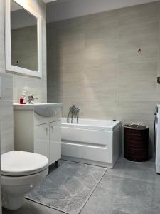 a bathroom with a toilet and a tub and a sink at City Center Sunny Apartment in Suceava